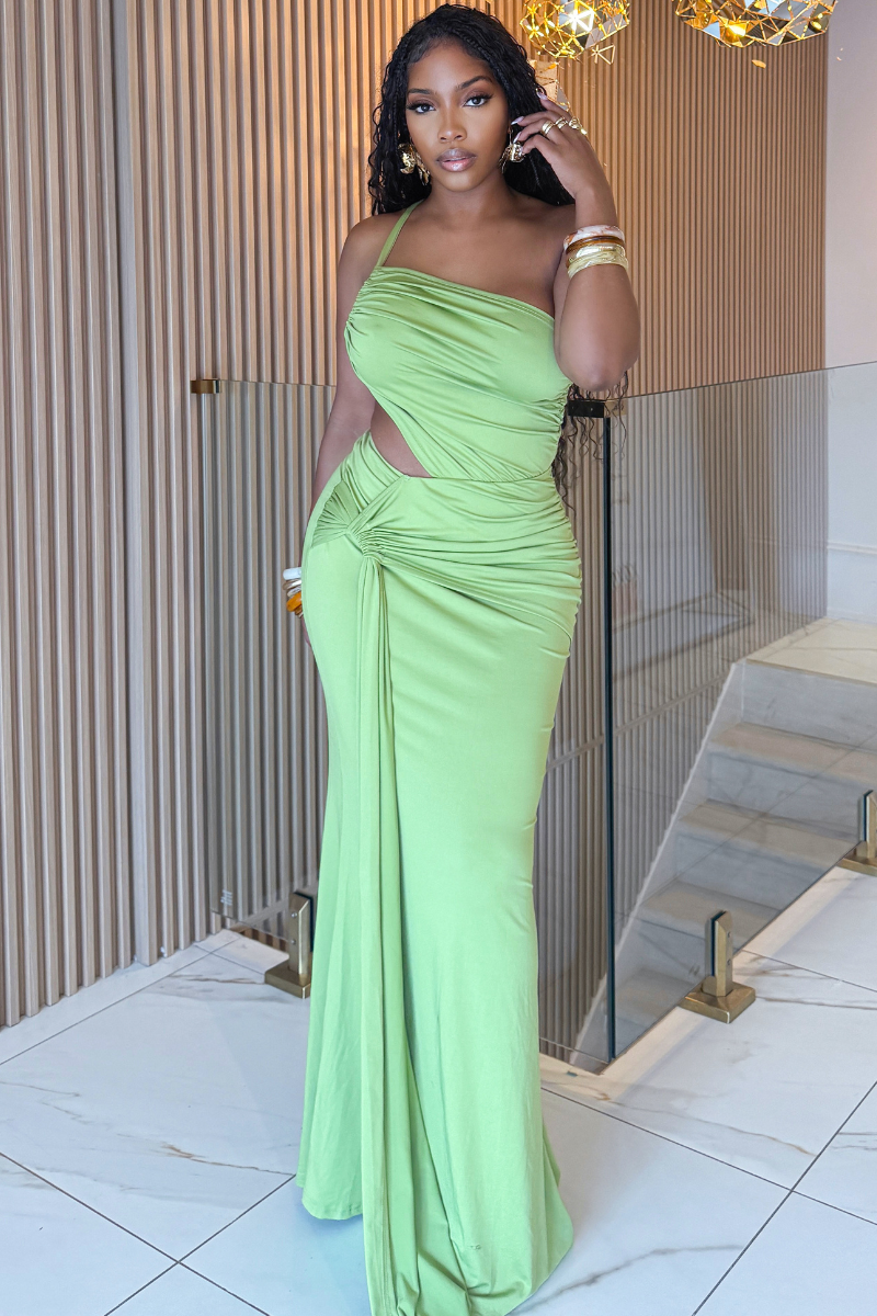Woman in a green evening gown standing indoors.