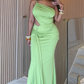 Woman in a green evening gown standing indoors with a neutral background