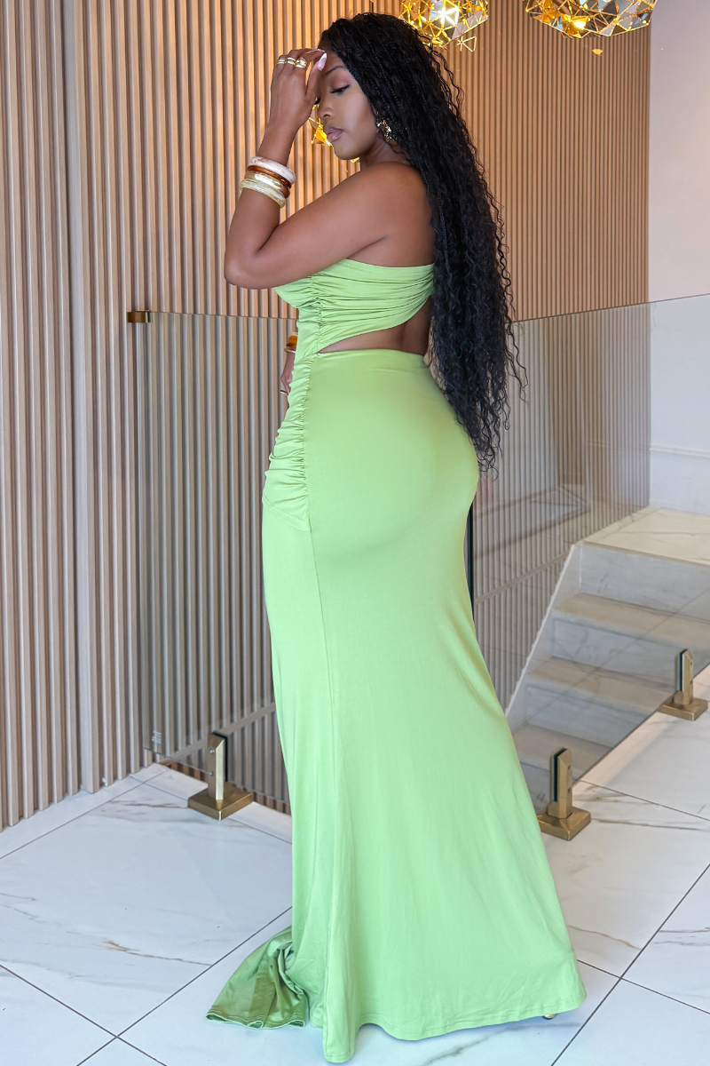 Woman in a green evening gown standing indoors with decorative elements in the background